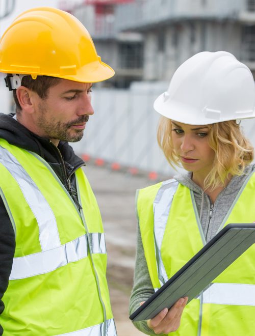 Woman in protective workwear and construction worker in construction site